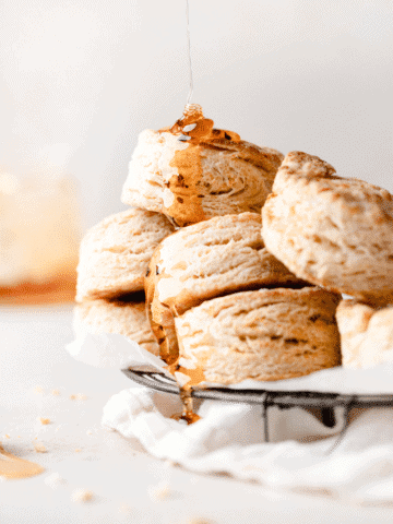 a pile of biscuits stacked on top of each other with a drizzle of honey
