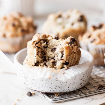 a muffin sitting in a white dish with a bite taken out of it