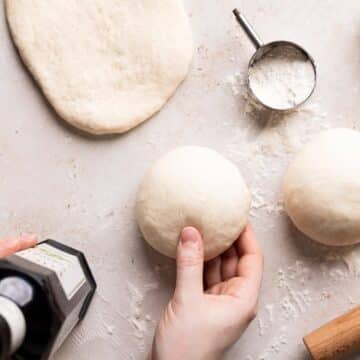 chewy pizza dough balls on a floured surface.