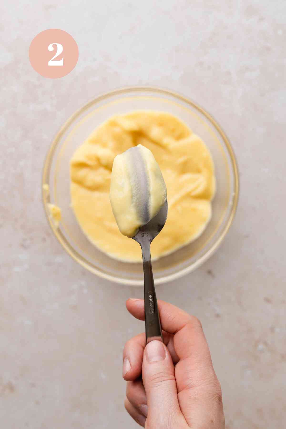 checking the consistency of the vanilla custard on a spoon.