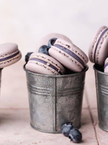 two metal cups full of blueberry macarons.