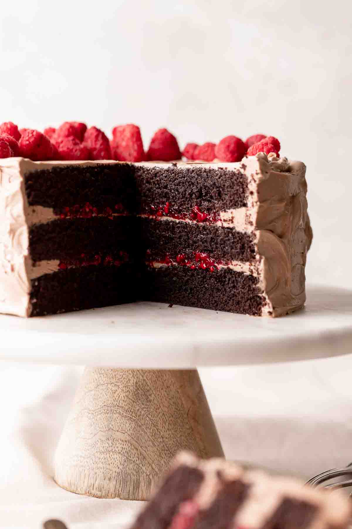 chocolate cake with raspberry filling on a cake stand.