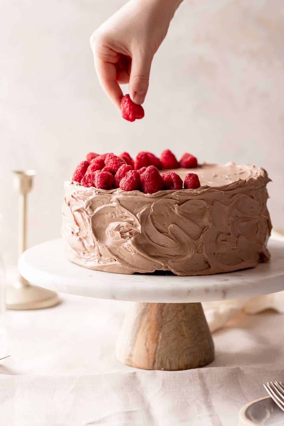 dark chocolate raspberry cake on a cake stand.