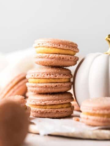 pumpkin macarons stacked on top of each other.
