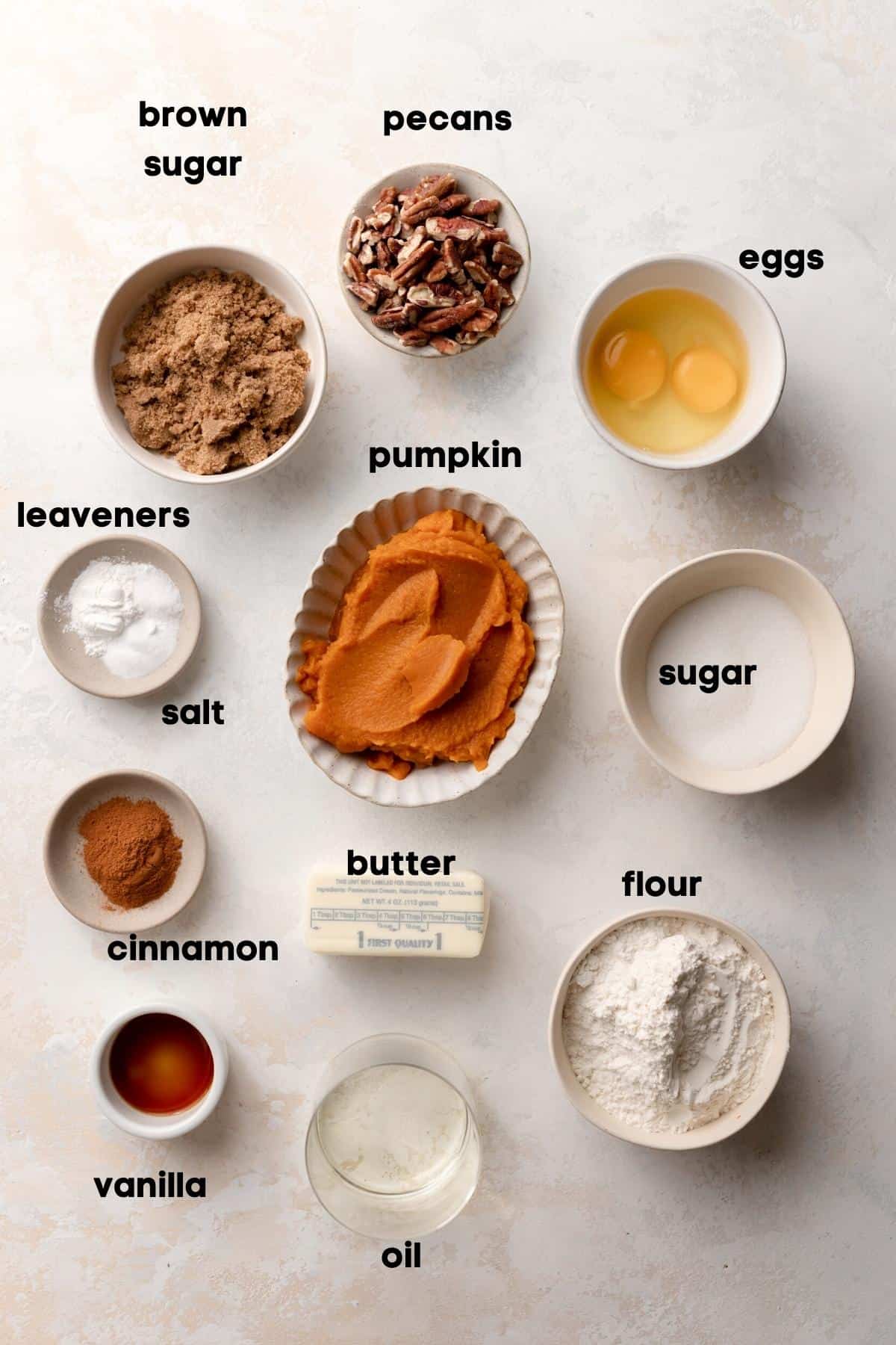 ingredients needed to make pecan pumpkin bread in bowls with labels.
