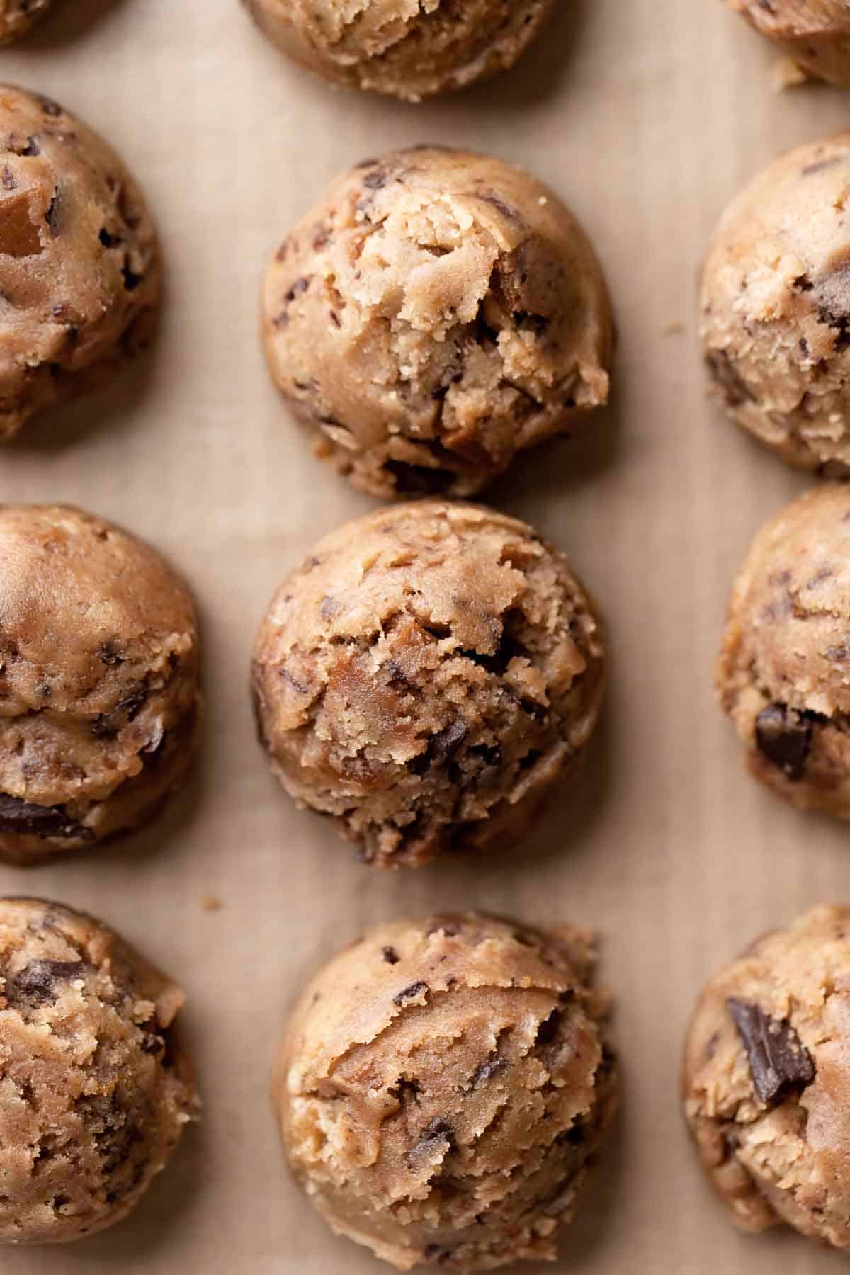 toffee cookie dough balls on a parchment lined baking sheet.