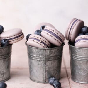 blueberry macarons filled with blueberry ganache in metal cups.