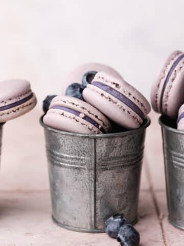 blueberry macarons filled with blueberry ganache in metal cups.