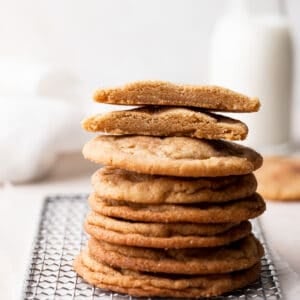 a stack of brown butter snickerdoodle cookies with the top two cut in half to show the chewy texture.