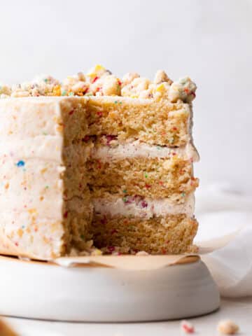 fruity pebble cake on a cake stand cut in half to show the texture.