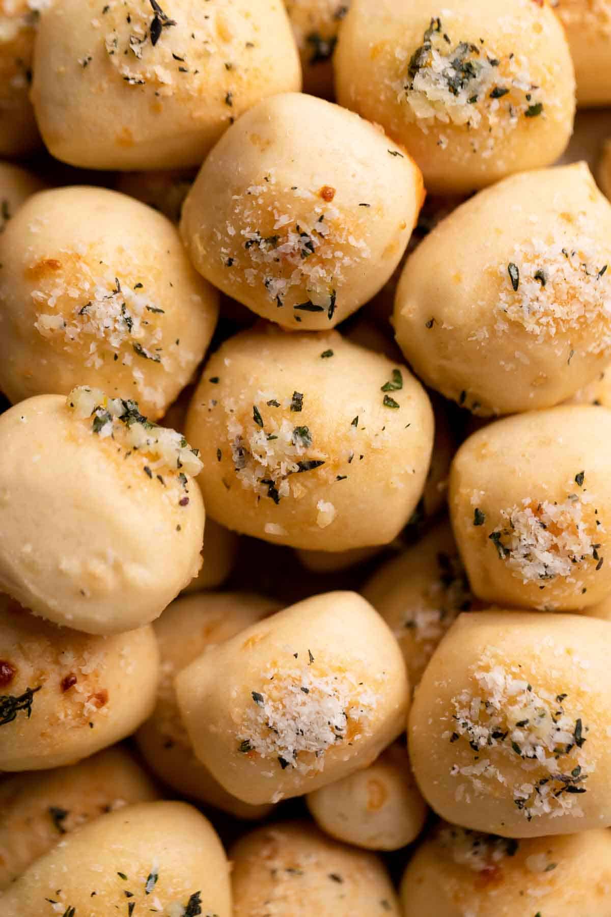 a pile of parmesan bread bites brushed with garlic butter and sprinkled with parmesan cheese.