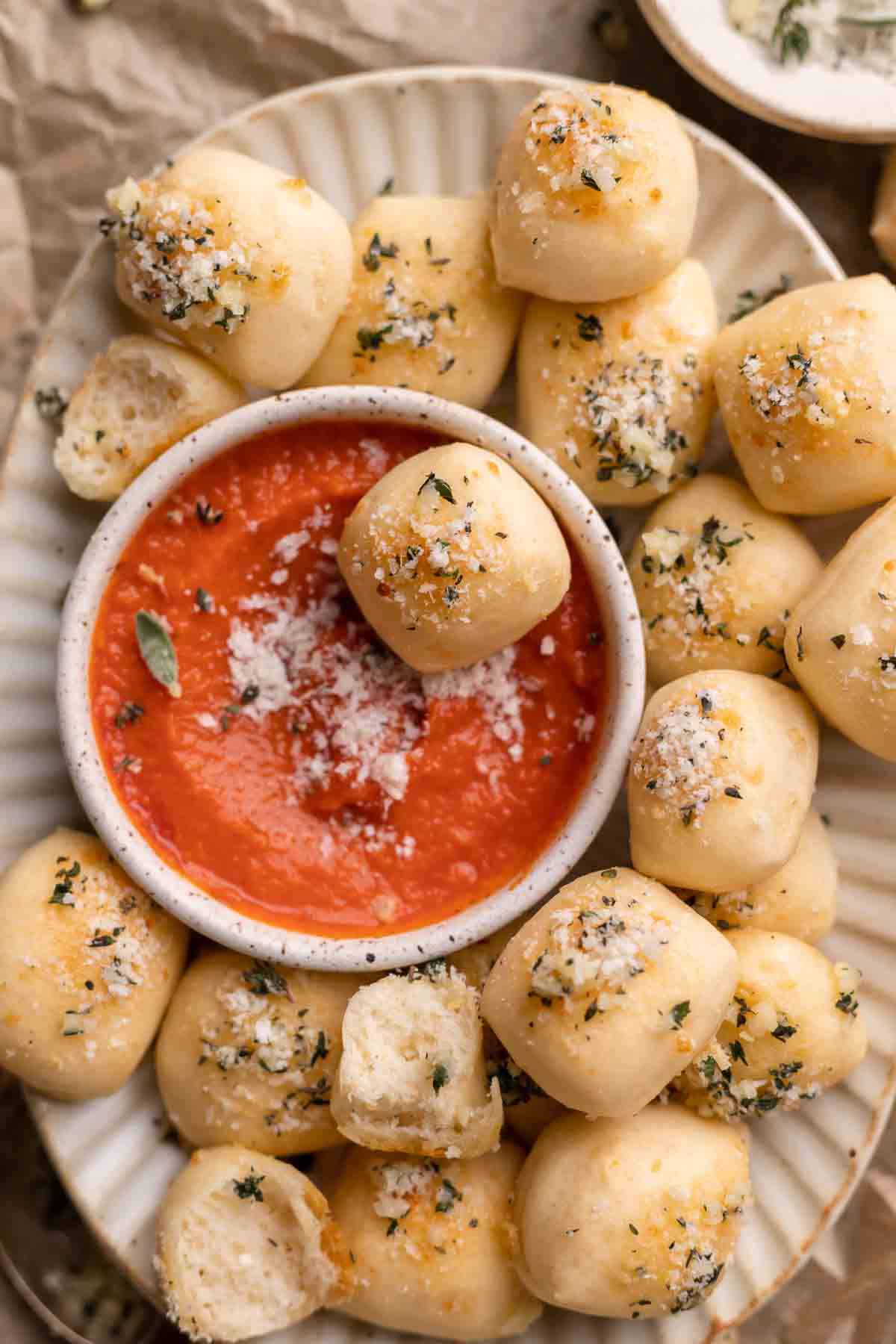 bread bites in a white bowl with a dish of marinara in the center.