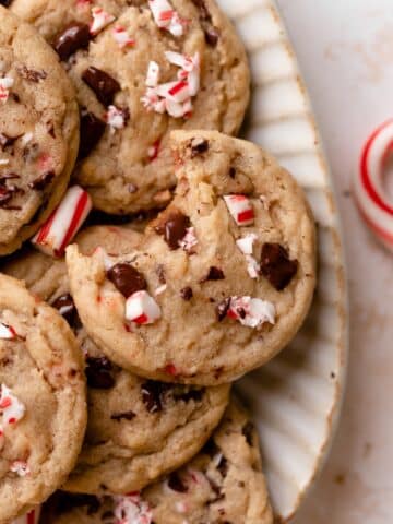 peppermint chocolate chip cookies in a white bowl with broken candy cane pieces.