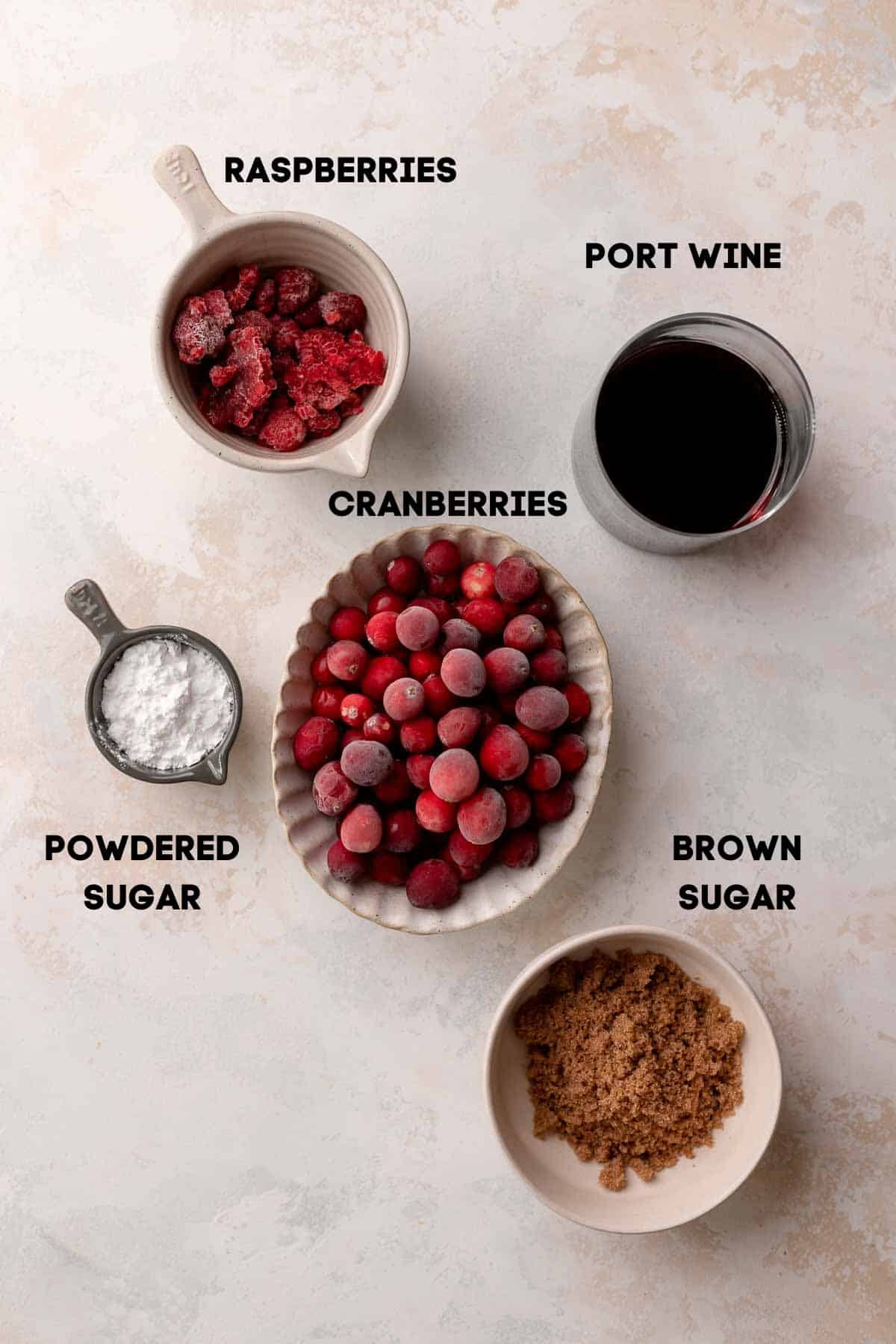 ingredients needed to make the cranberry raspberry jam in bowls with labels.