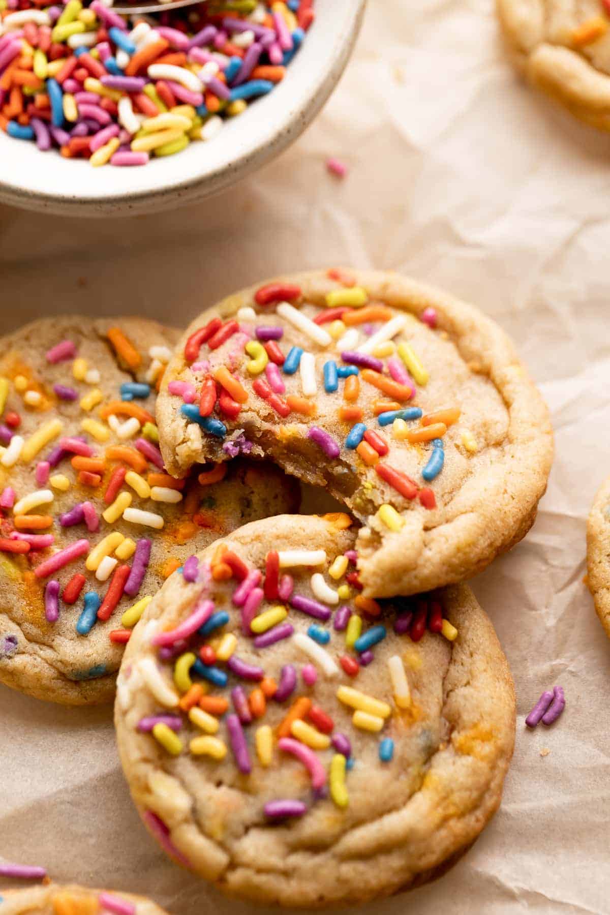funfetti cookie covered in rainbow sprinkles with a bite taken out of it.