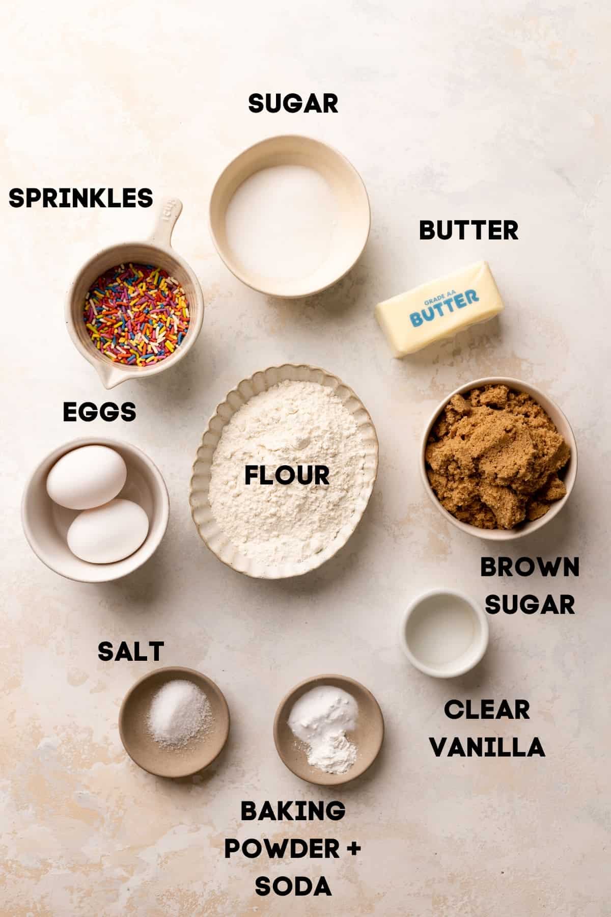 ingredients needed to make sugar cookies in bowls with labels.