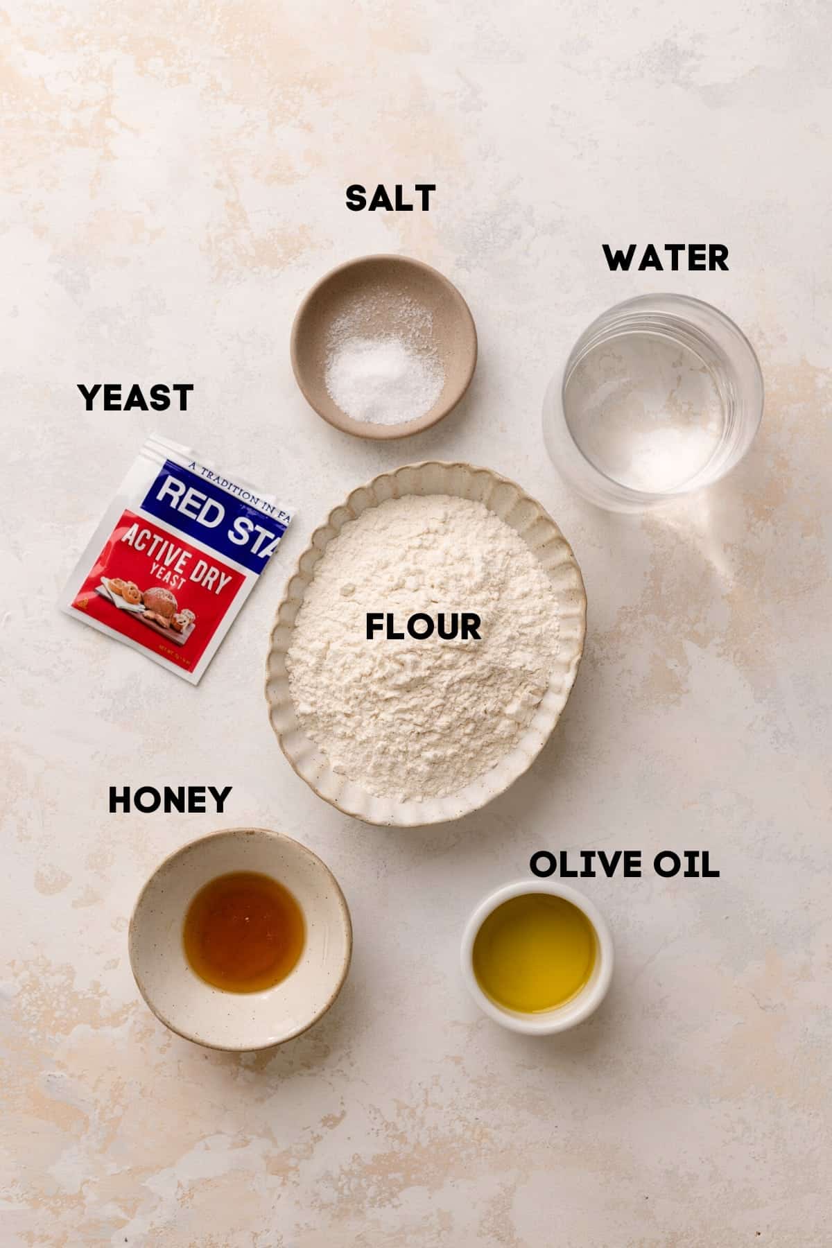 ingredients needed to make pizza dough in bowls with labels.