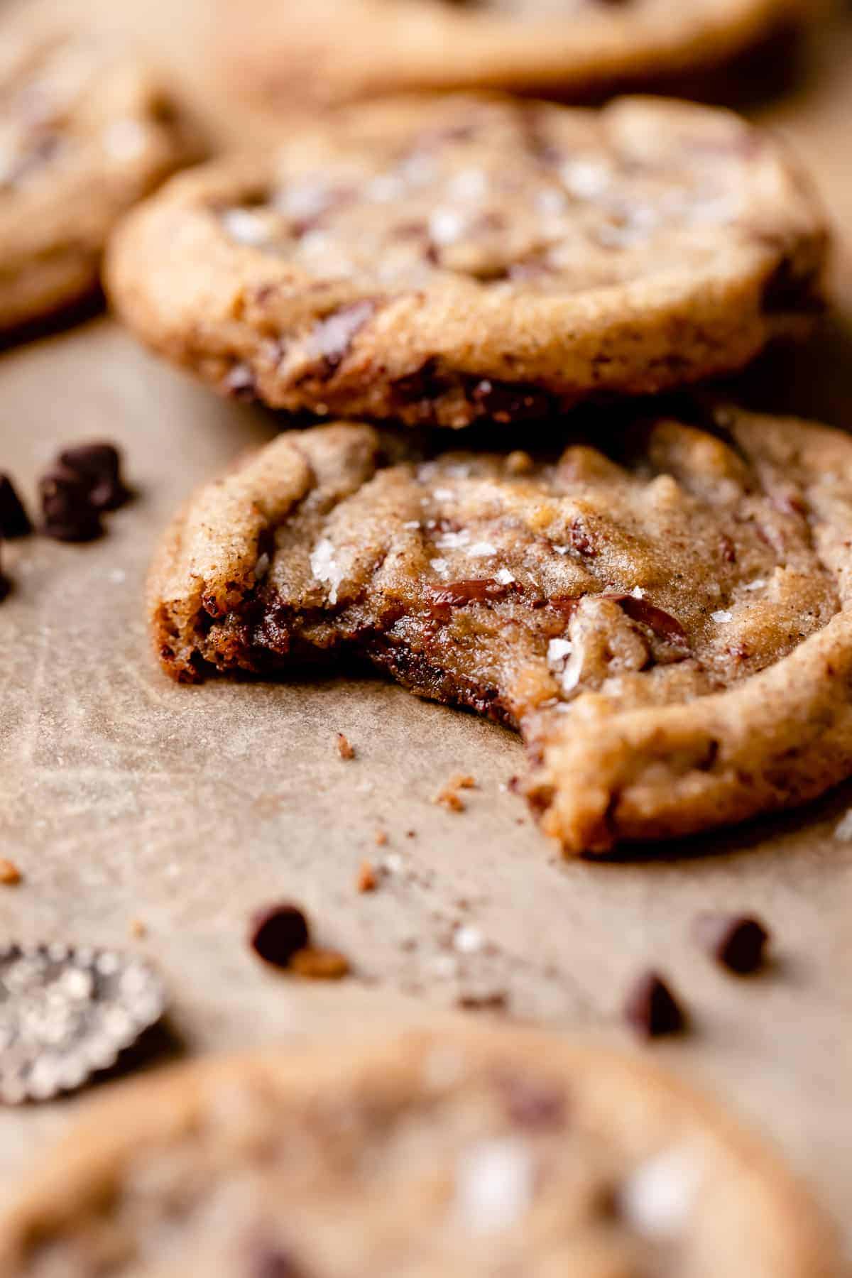 a coffee cookie topped with chocolate chips with a bite taken out of it.