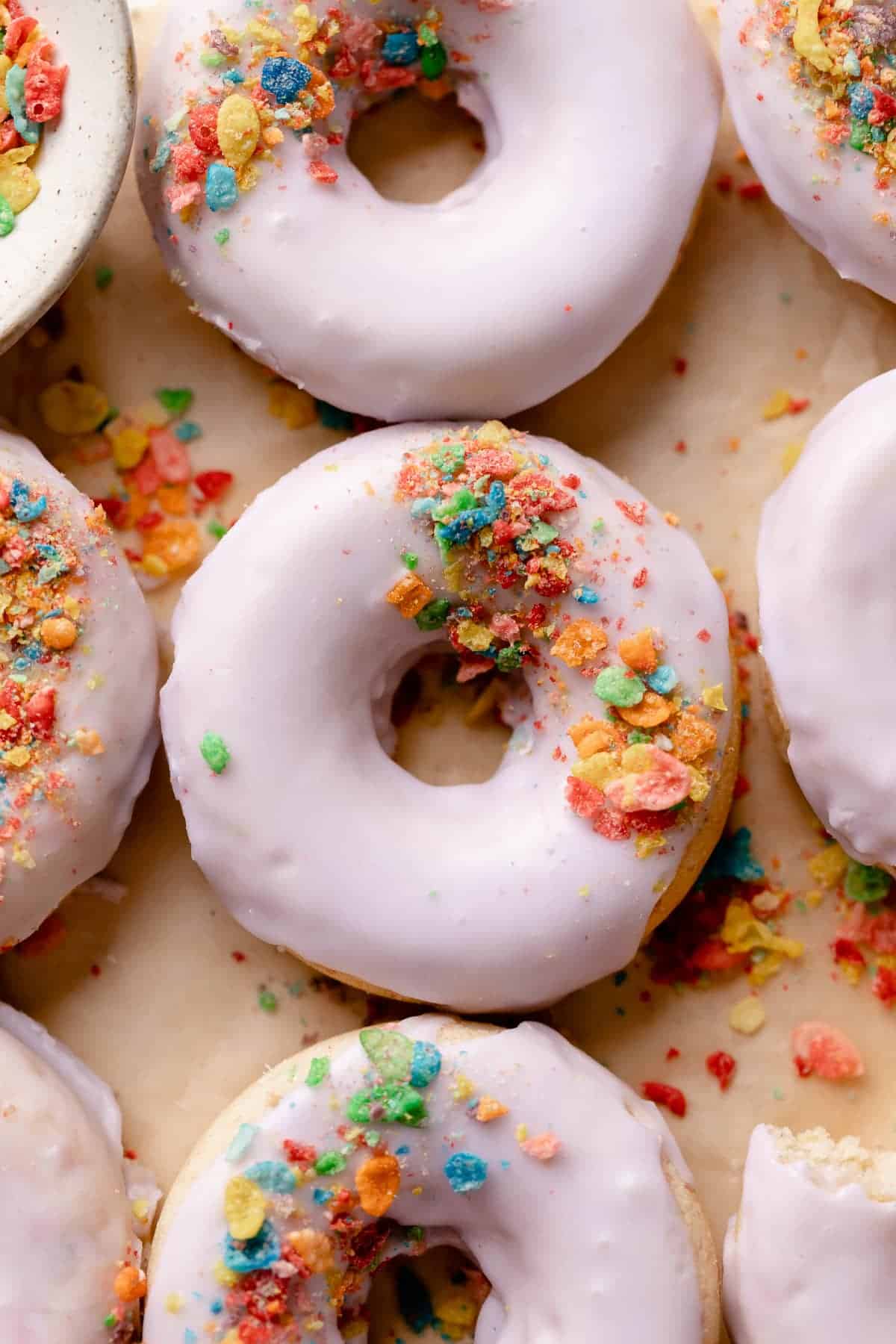 fruity pebble donuts topped with fruity pebbles cereal.