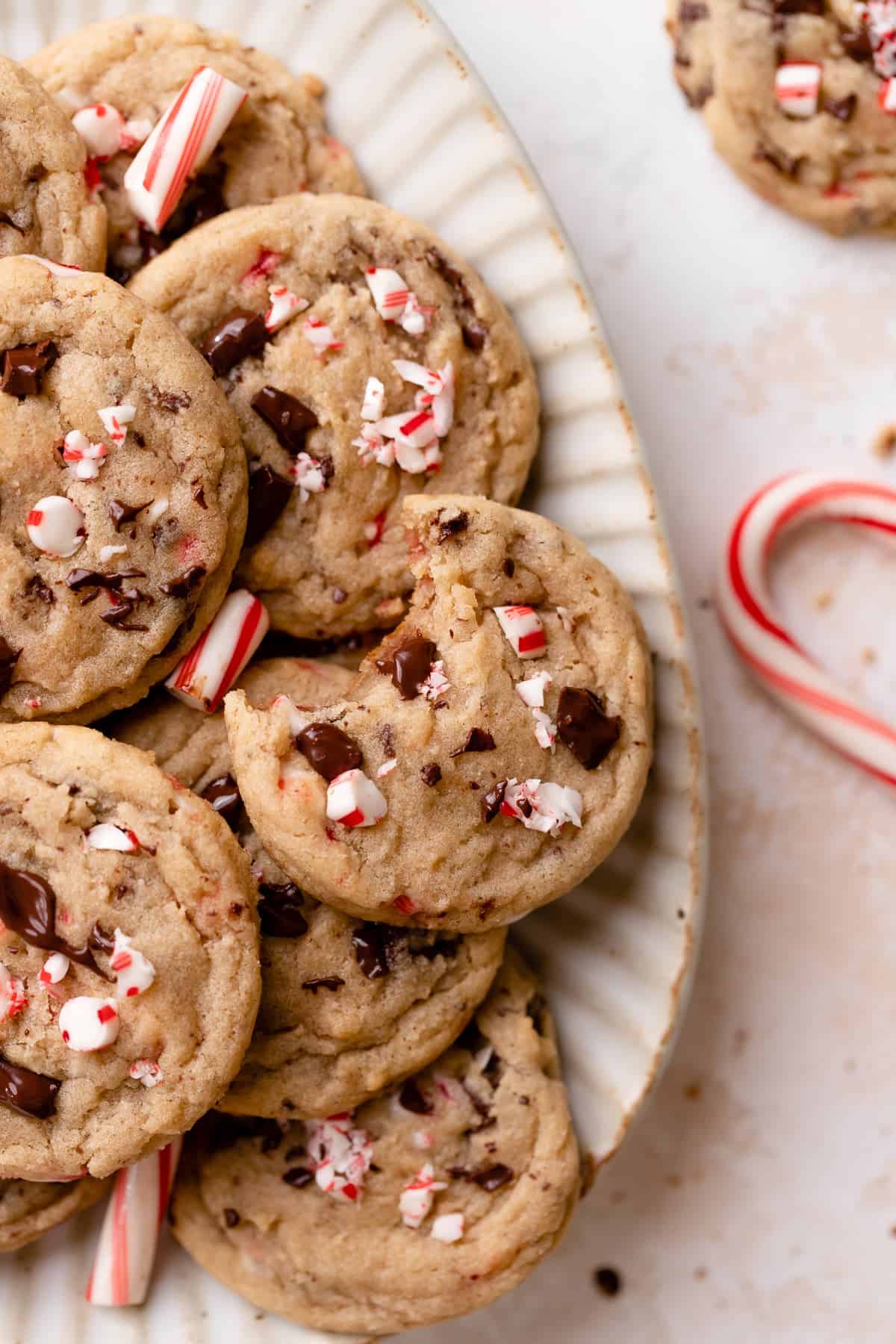 peppermint chocolate chip cookies on a white plate with candy cane pieces.