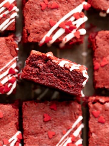 red velvet brownies drizzled with cream cheese glaze and red heart sprinkles.