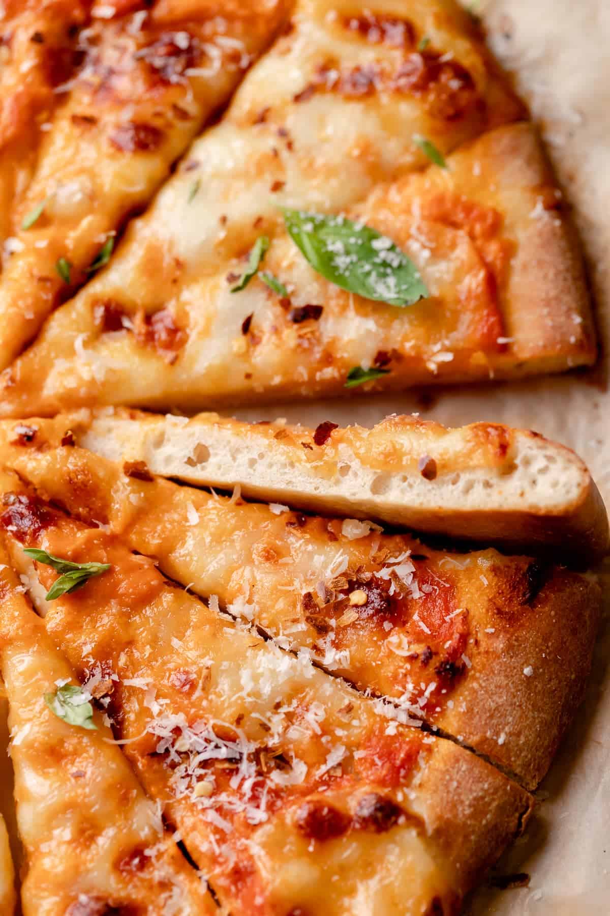 a slice of vodka sauce pizza on its side to show the bubbly dough texture and rich vodka sauce color.