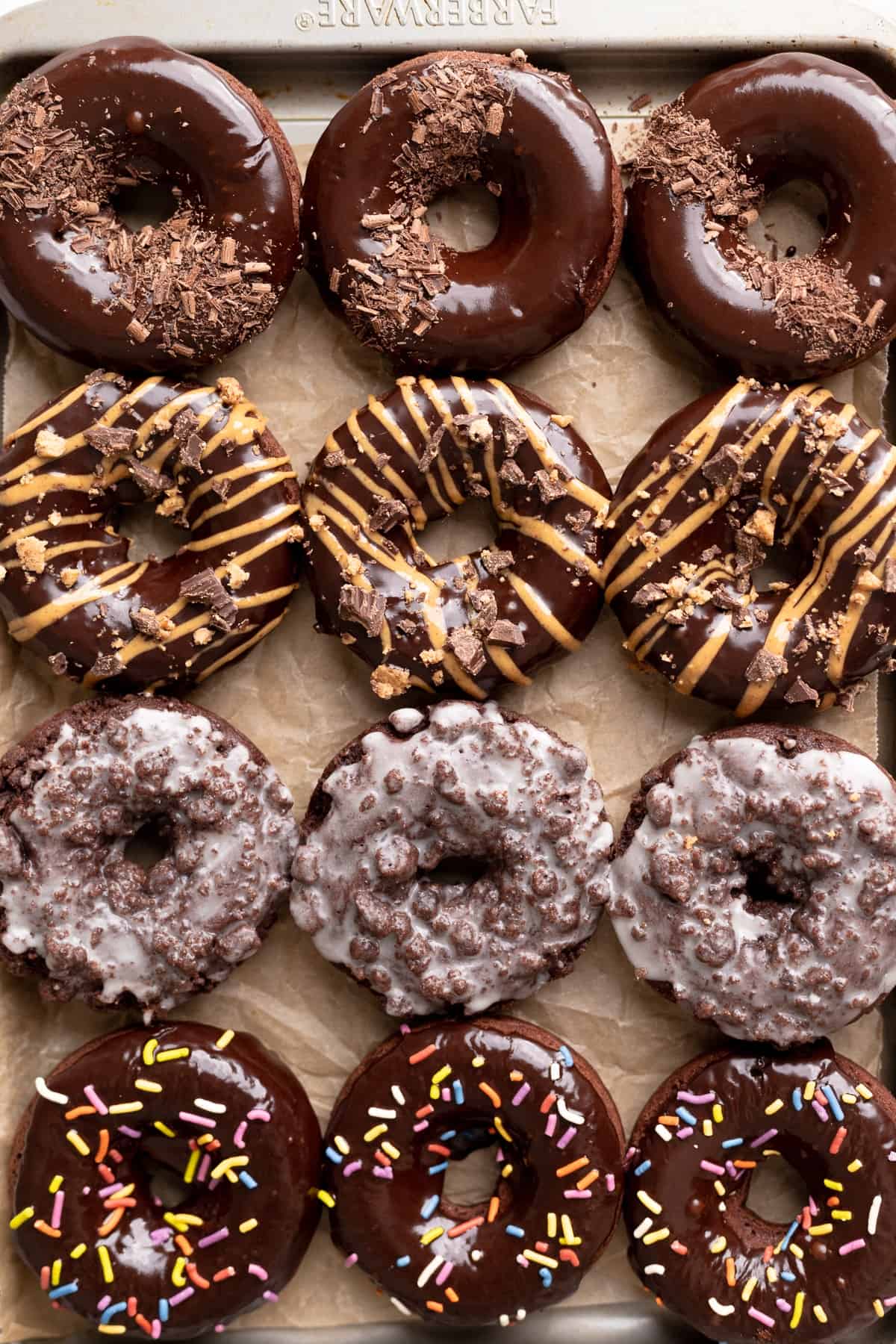 chocolate baked donuts four different ways on a baking tray.
