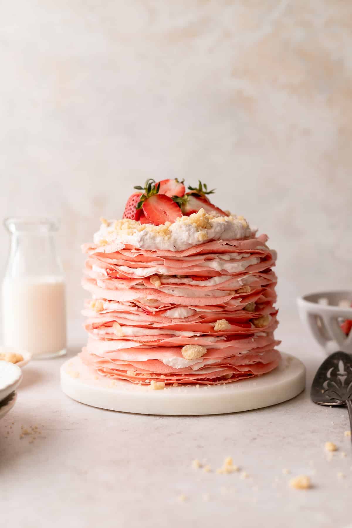 strawberry crepe cake topped with whipped cream and strawberries.