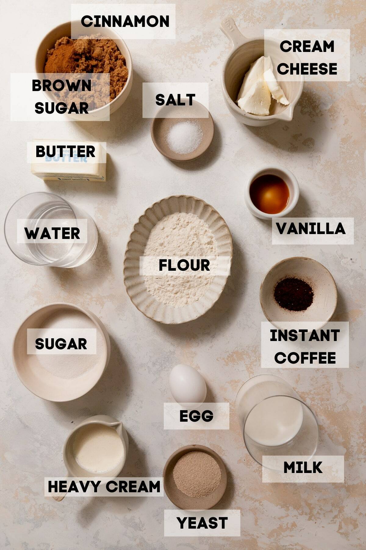ingredients needed to make cinnamon rolls in bowls with labels.