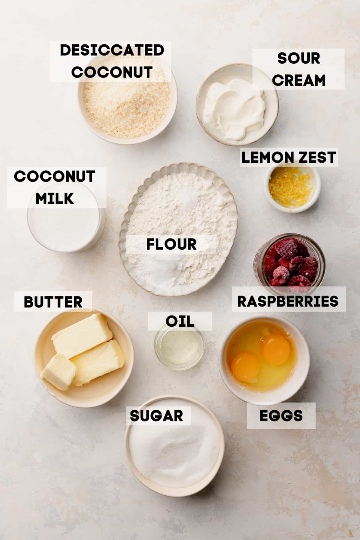 ingredients needed to make raspberry muffins in bowls with labels.