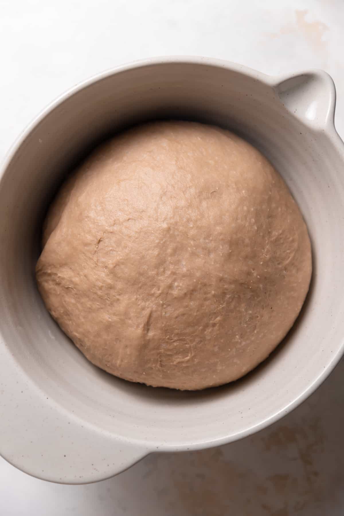 cinnamon roll dough that has doubled in size in a mixing bowl.