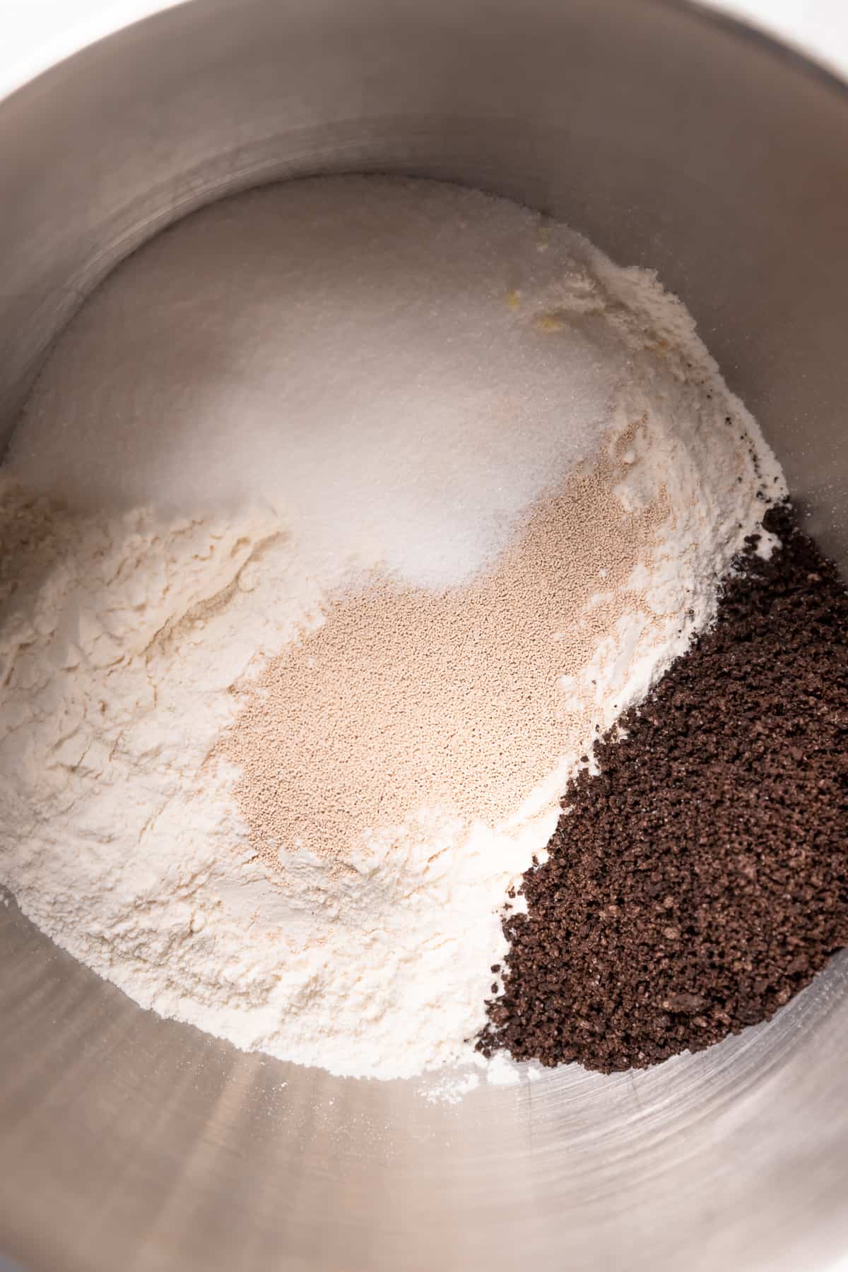 flour, oreo crumbs, yeast, and sugar in a mixing bowl.