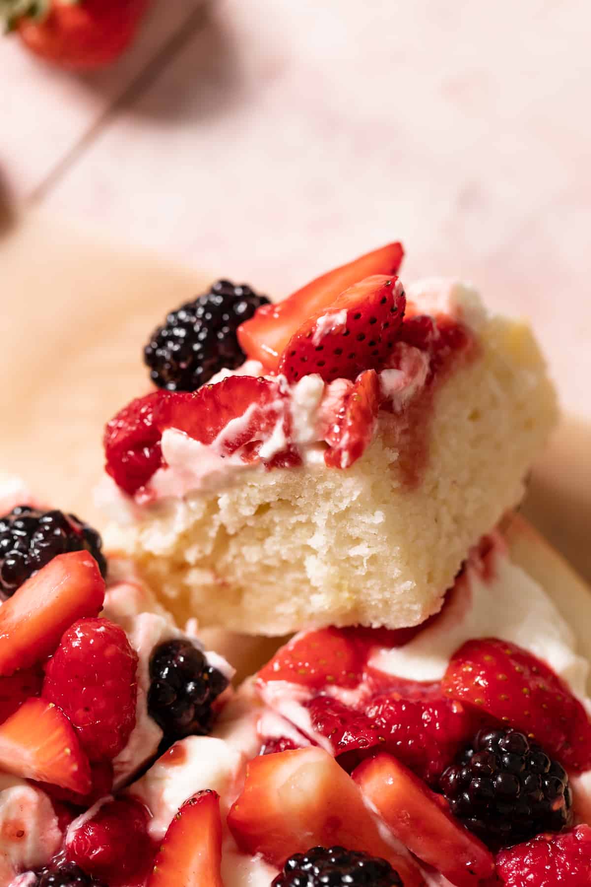 a slice of lemon berry mascarpone cake with fresh berries on top.