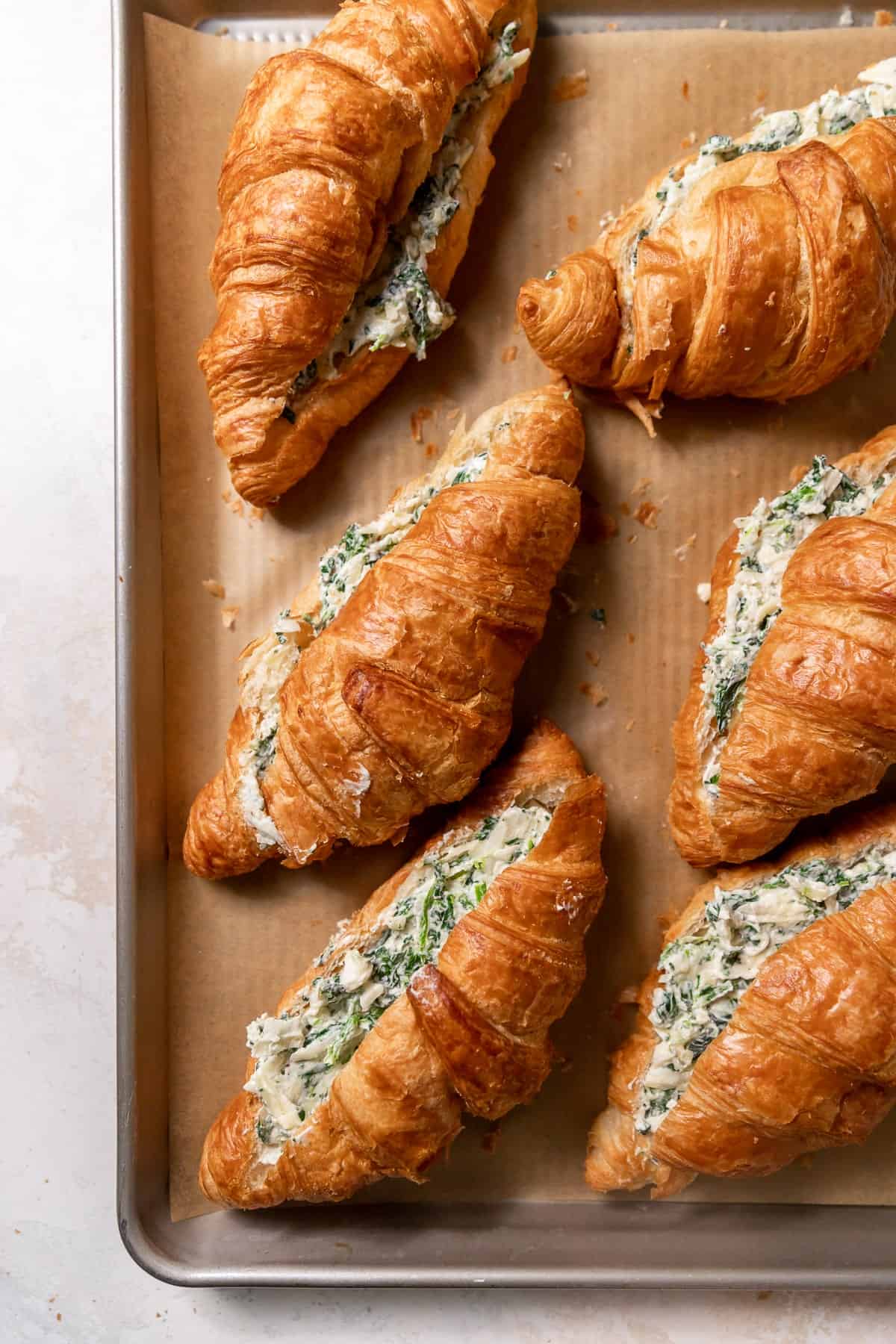 croissants with cheese and spinach filling on a baking sheet.