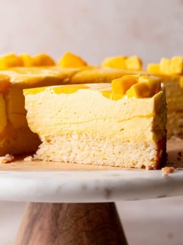 mango mousse cake on a white marble cake stand.