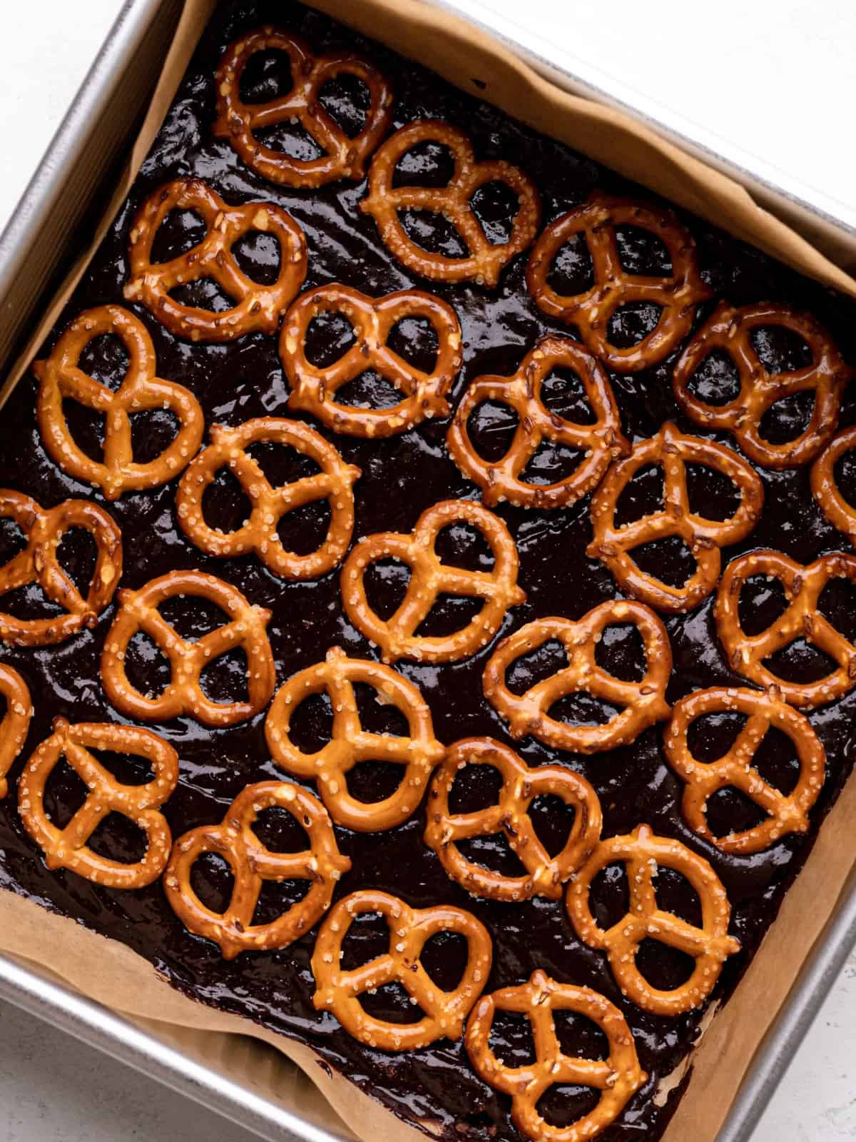 mini pretzels layered on top of brownie batter in a baking pan.