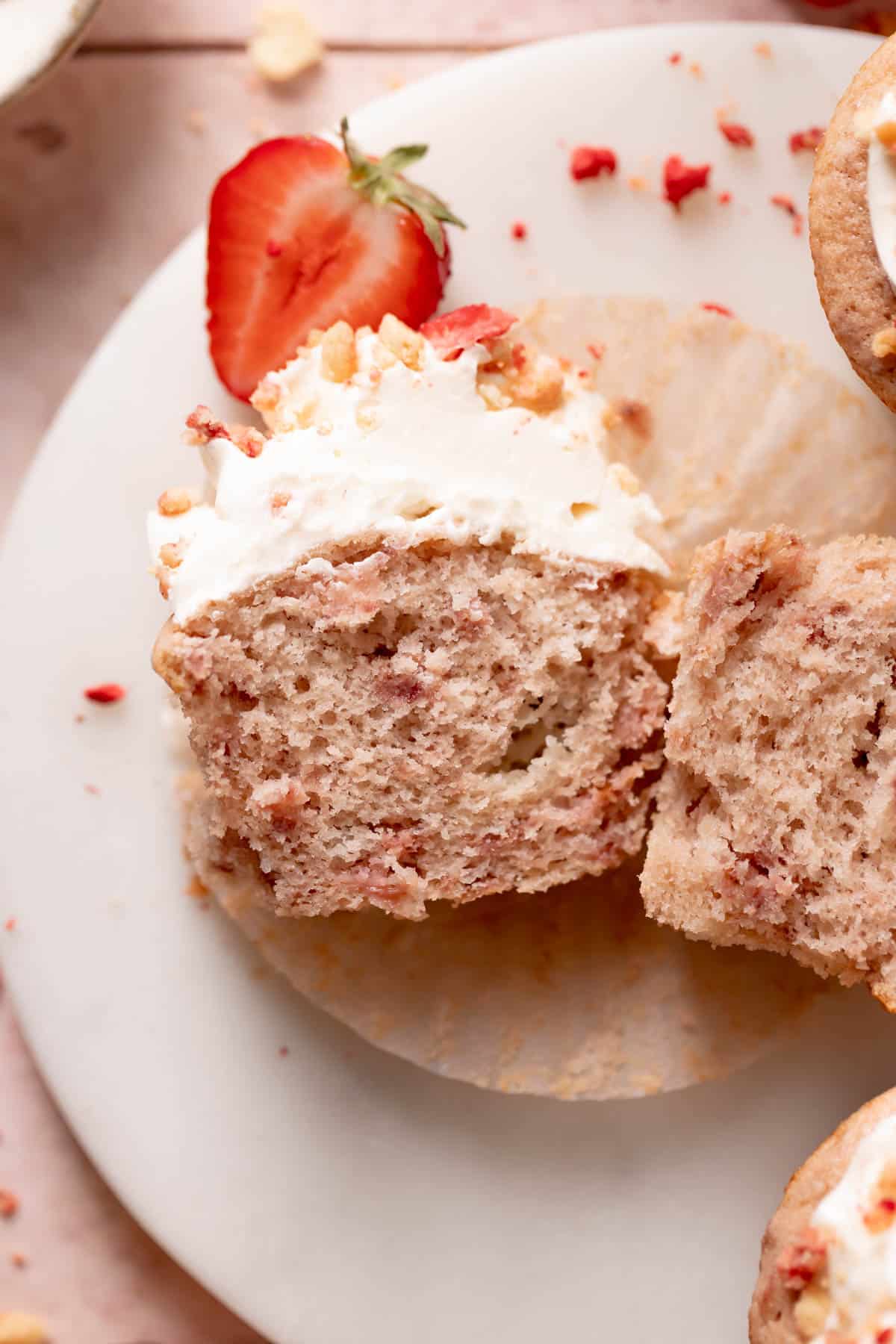 strawberry shortcake cupcake cut in half on a white plate.