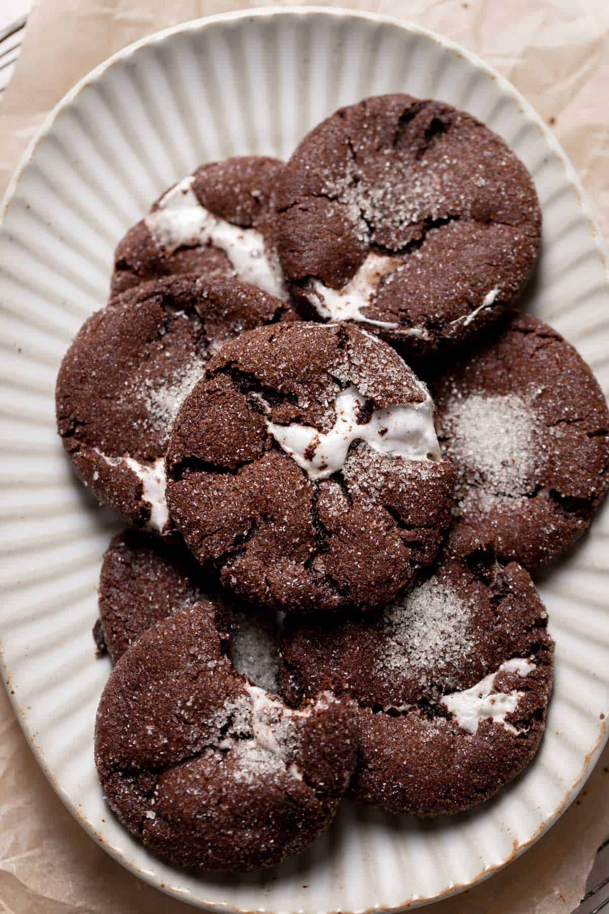 a pile of chocolate marshmallow cookies on a white plate.