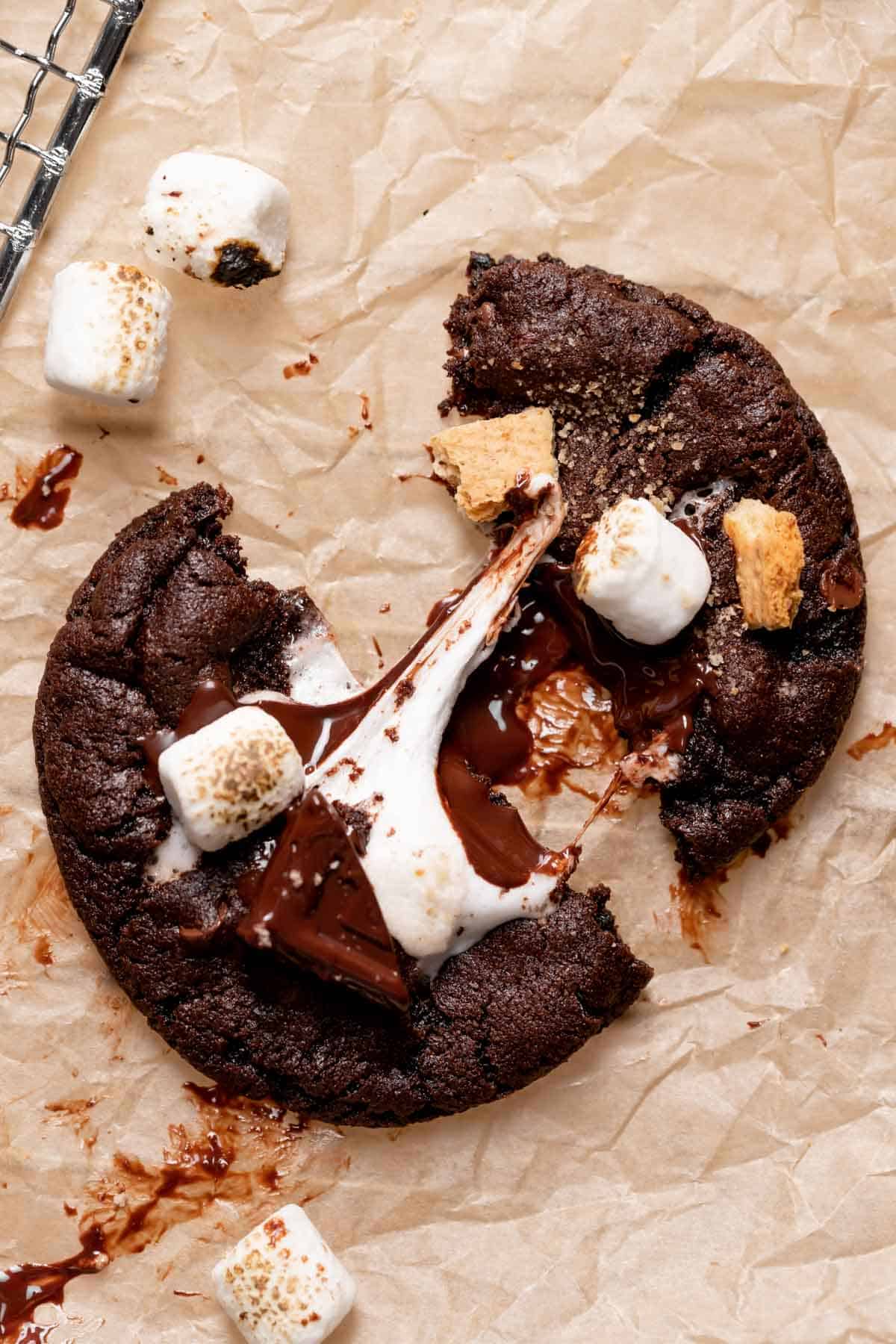 chocolate smores cookie pulled in half on parchment paper.