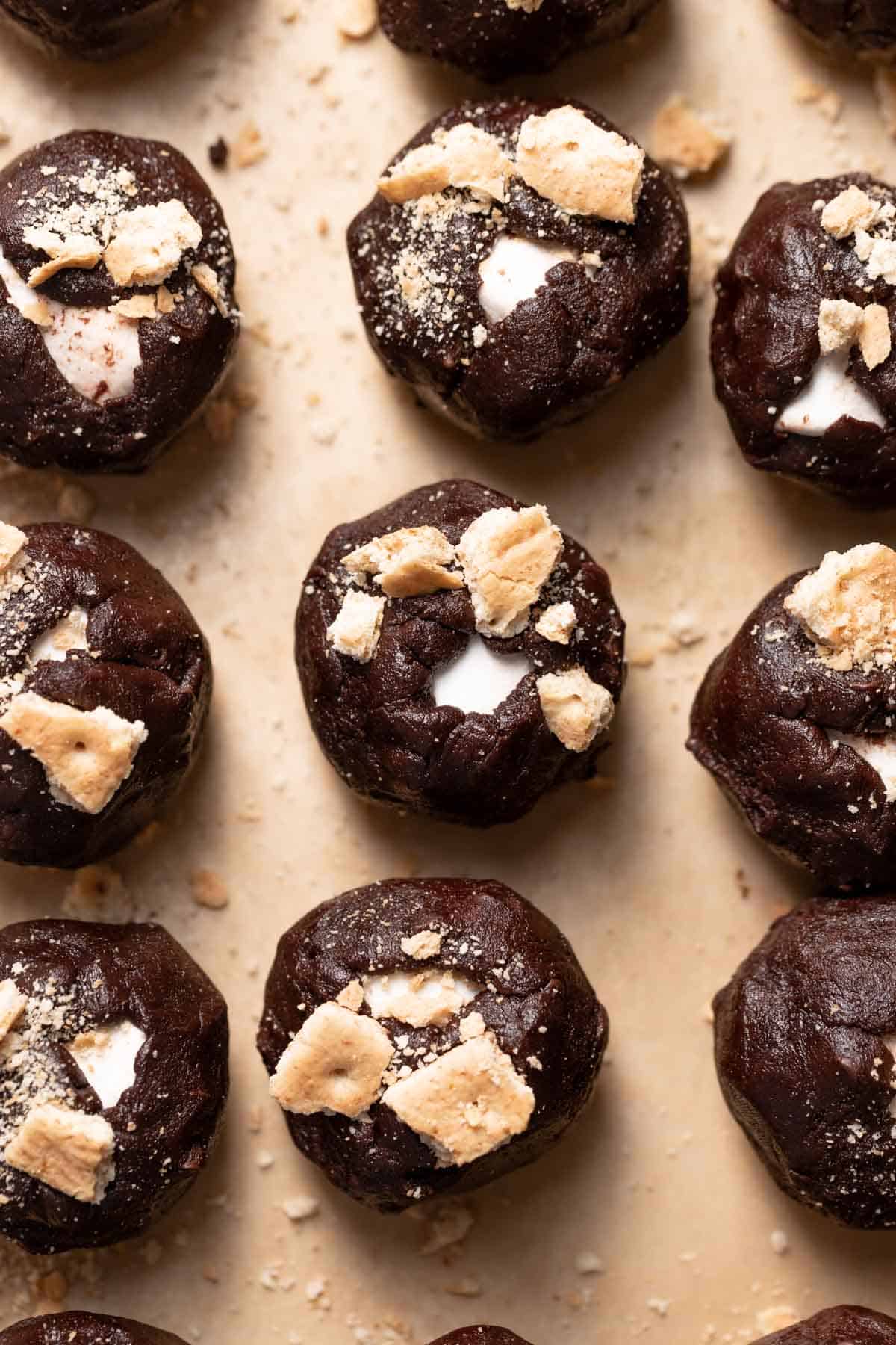cookie dough balls topped with graham crackers on a baking tray.