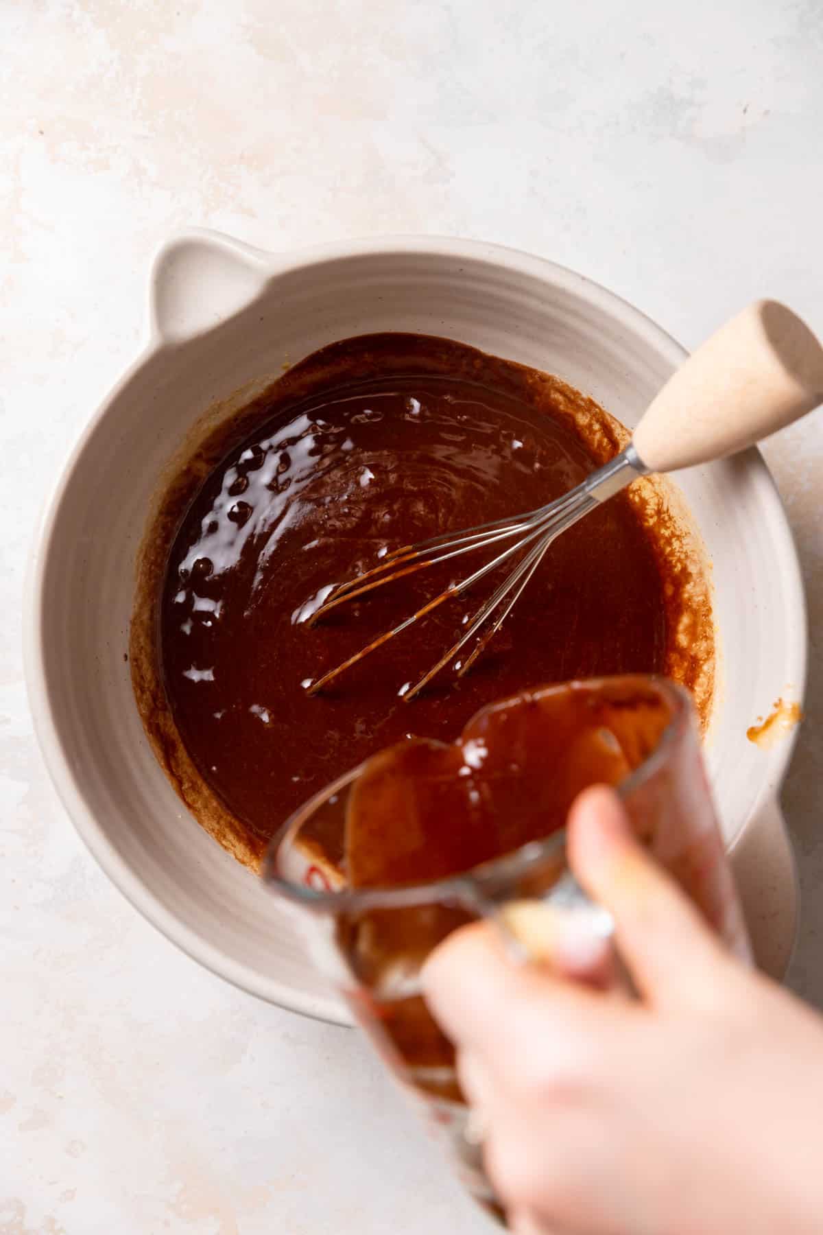 whisking chocolate into the bowl of brownie batter.