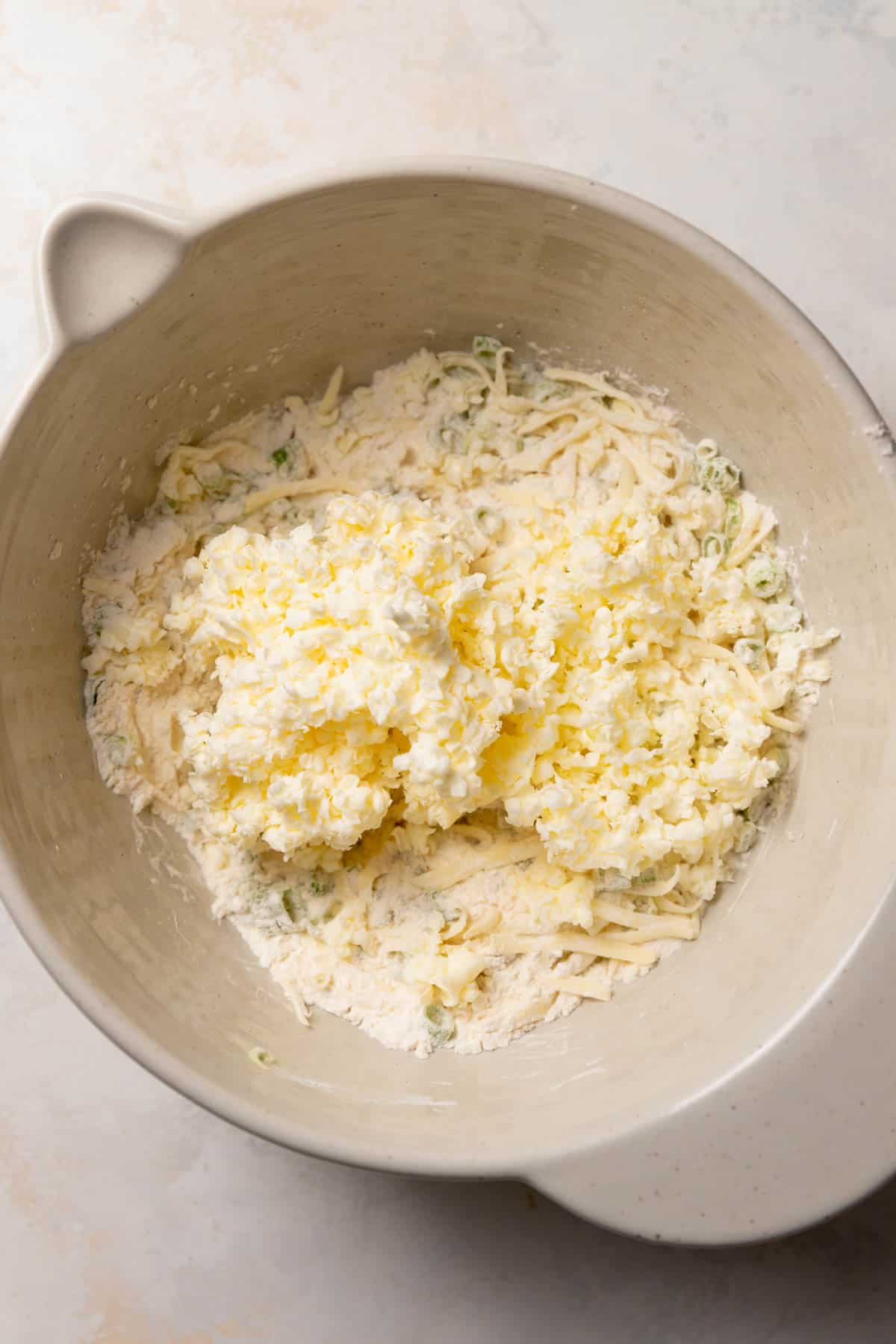 a mixing bowl of the dry ingredients with the butter on top.