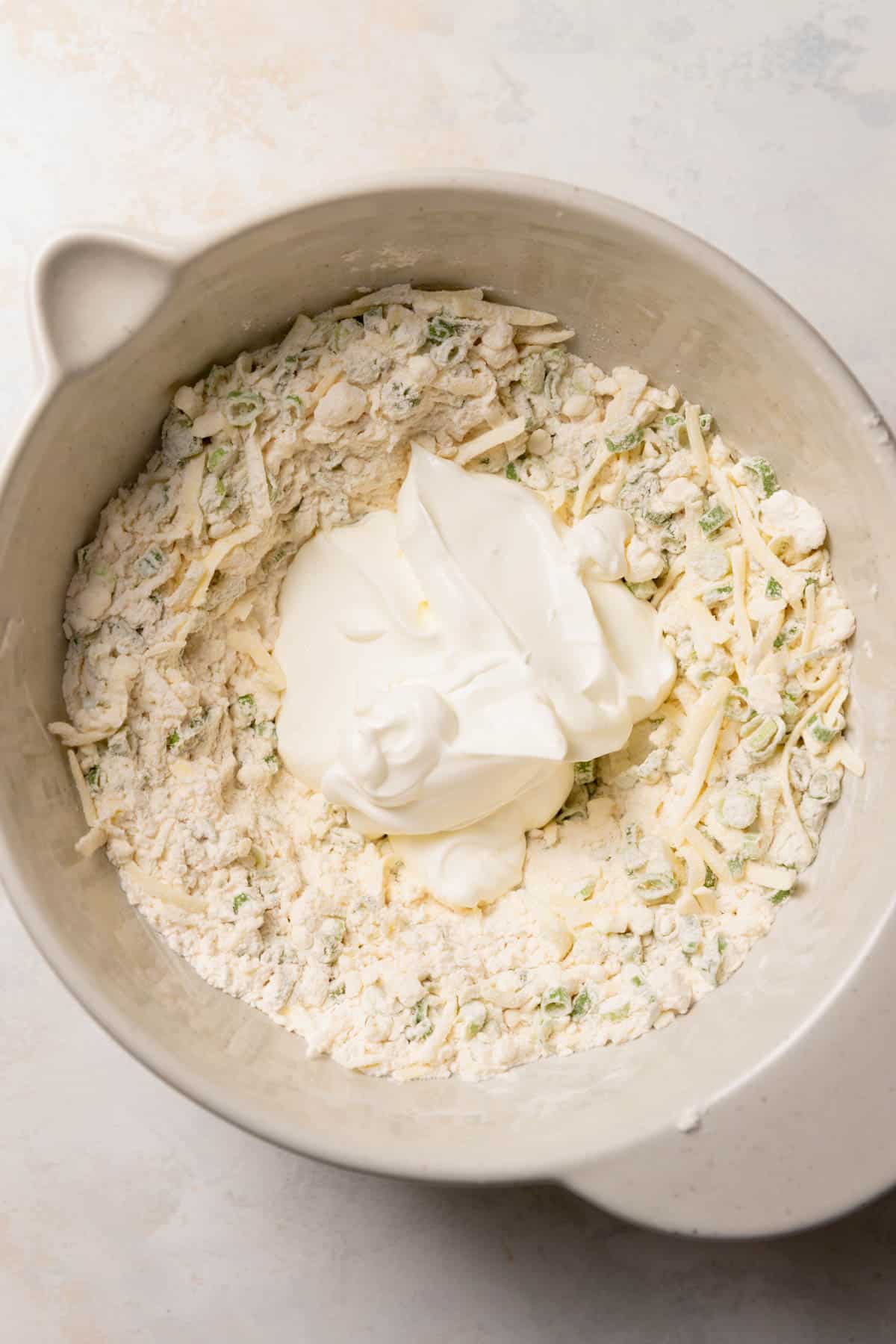 a bowl with the dry ingredients and sour cream on top of it.