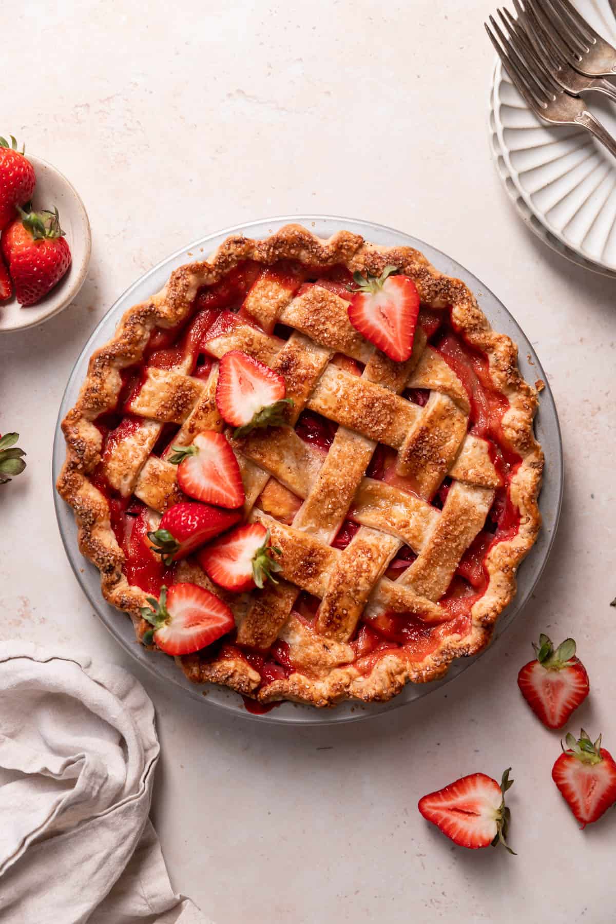 strawberry peach pie in a pie pan with fresh berries on top.