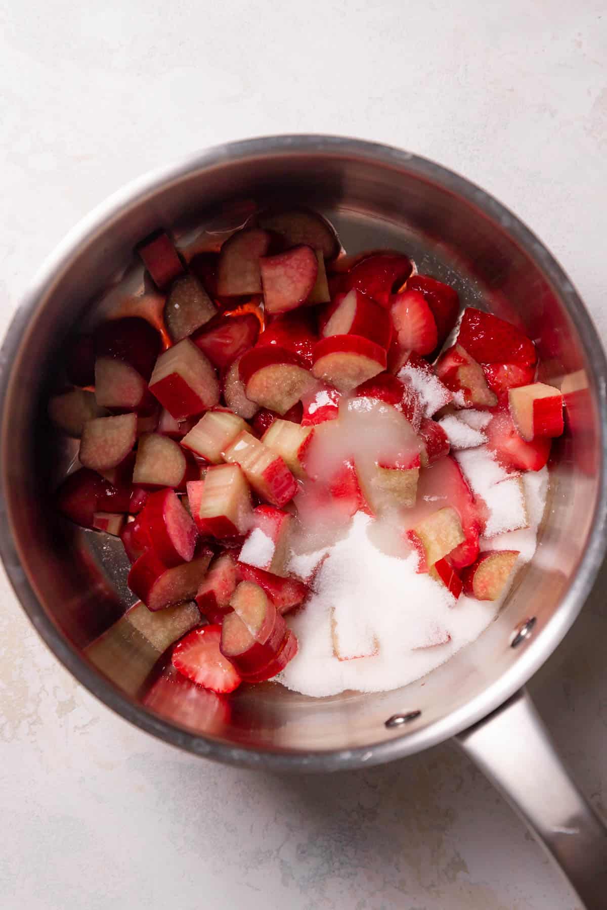 strawberries and rhubarb in a pot with sugar.