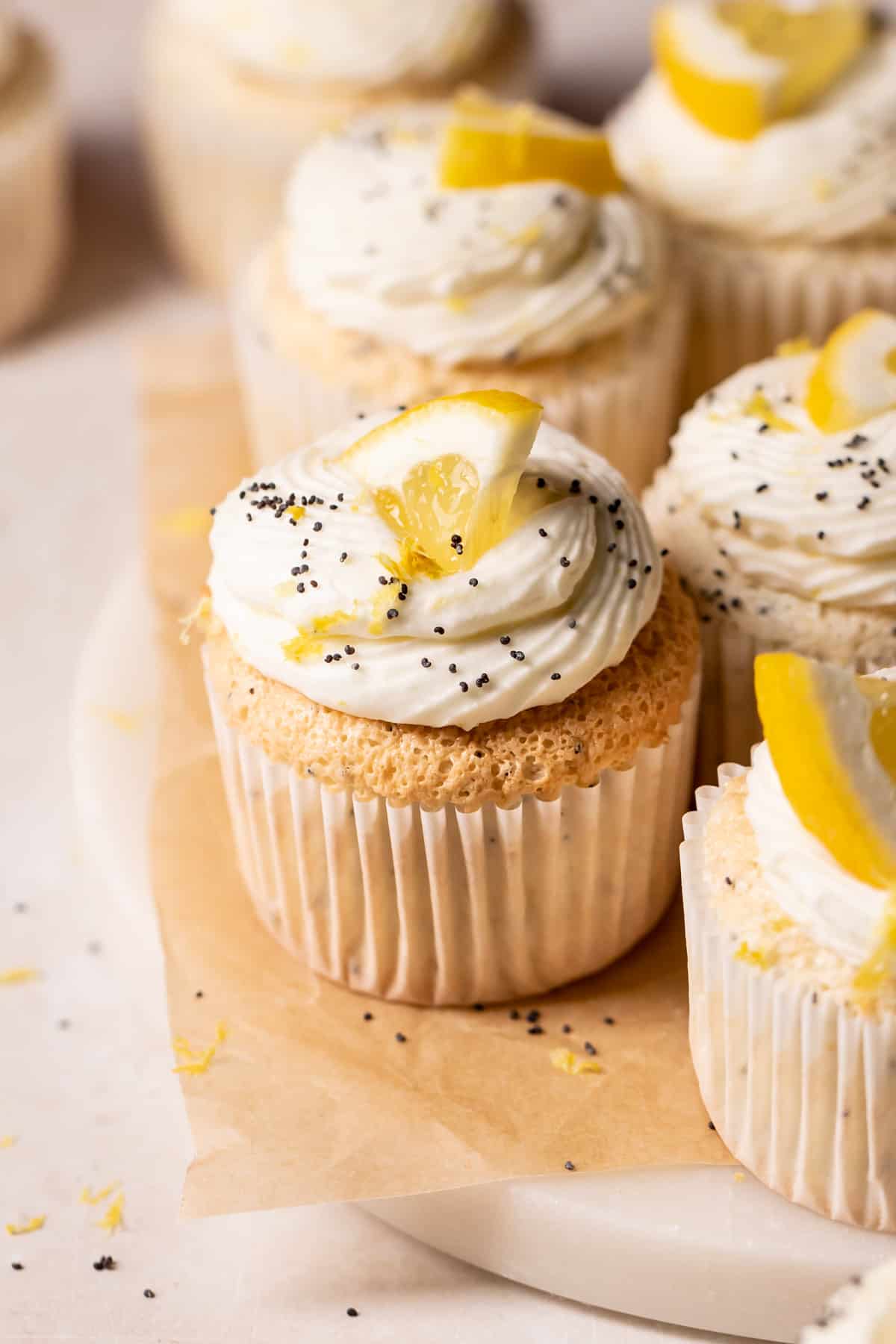 lemon poppy seed cupcakes with lemon frosting and fresh lemon wedge.