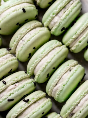 mint chocolate chip macarons on a baking tray.