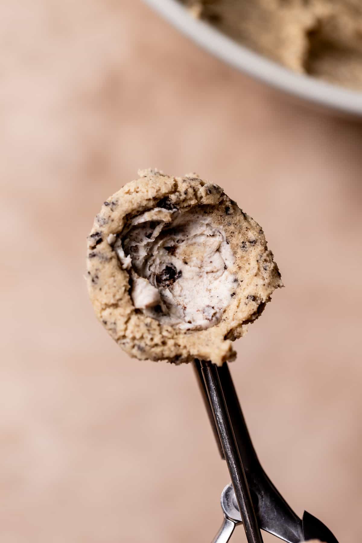 cookie scoop with cookie dough and a ball of cream cheese in the center.