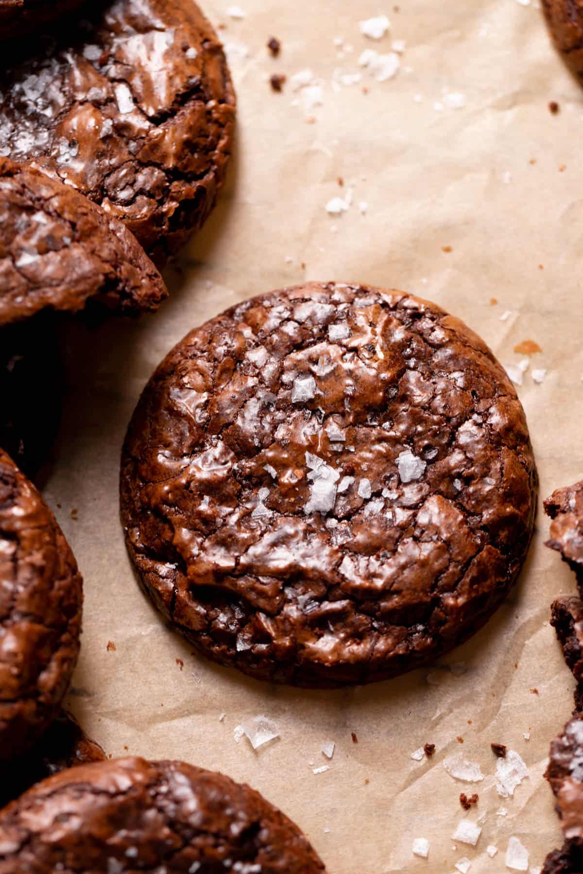 a brownie cookie on brown parchment paper sprinkled with flaky sea salt.