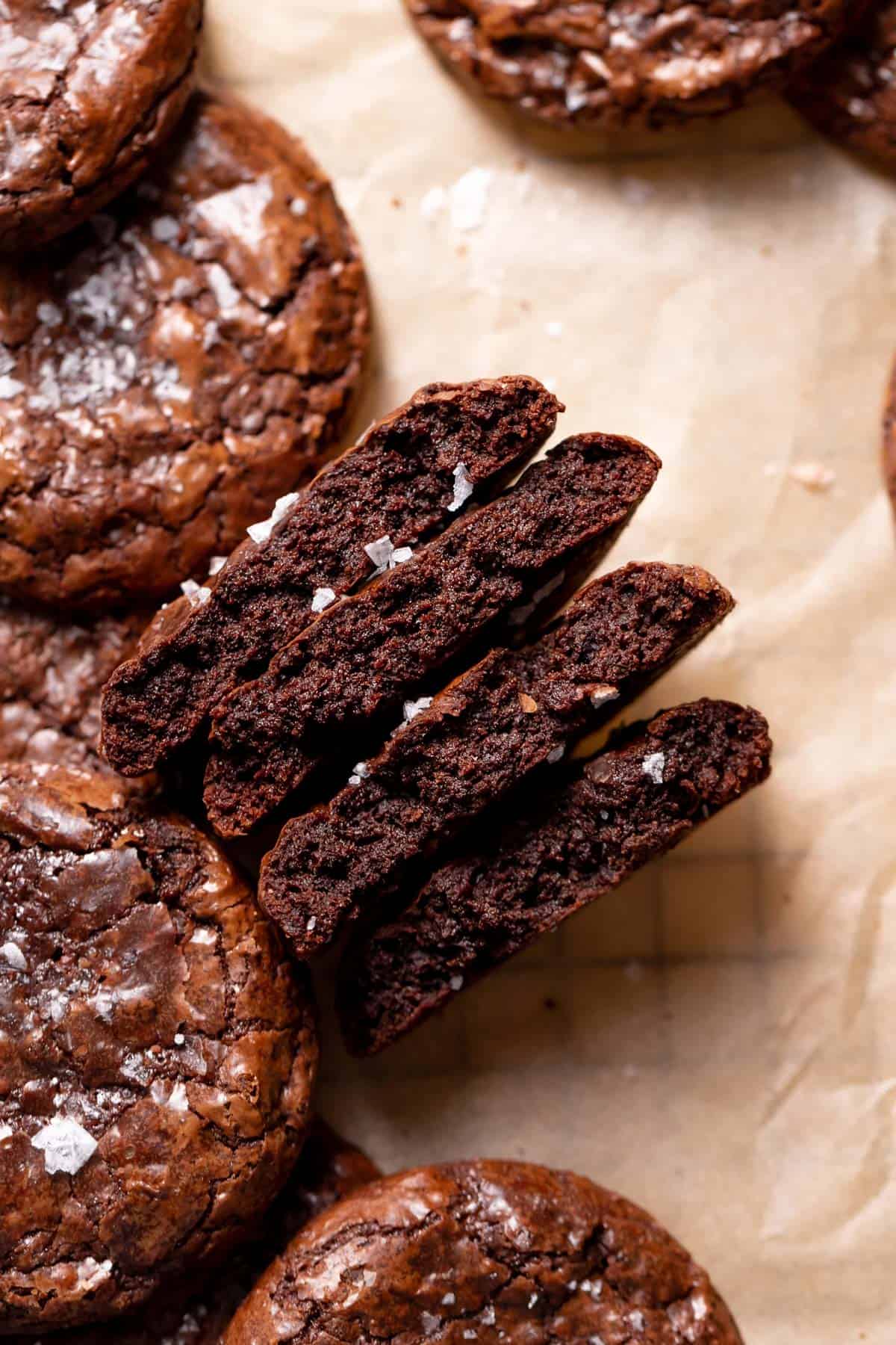 a stack of brownie crinkle cookies cut in half to show their fudgy texture.